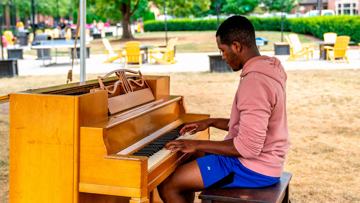 A student playing the piano outside on third street.