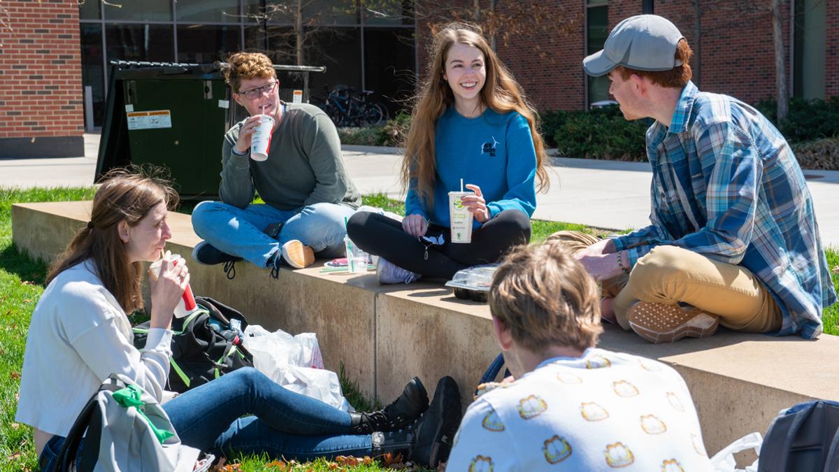 Photo of a group of students sitting outside on campus