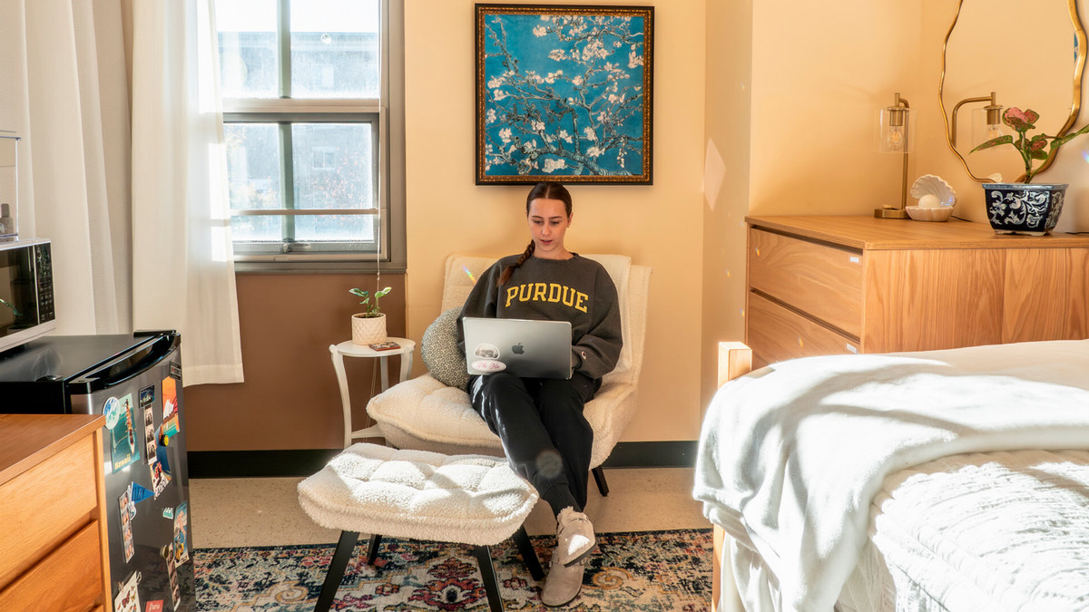 A student in her dorm room working on her computer.