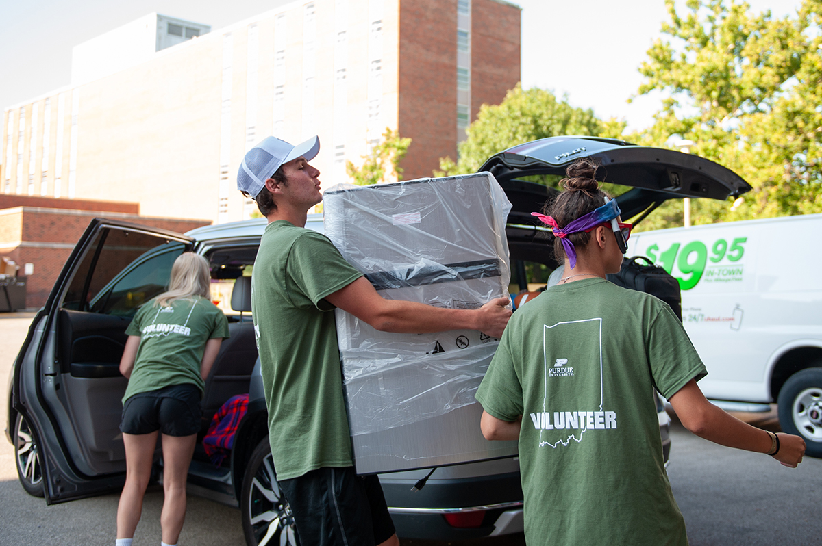 Student volunteer carries mini-fridge.