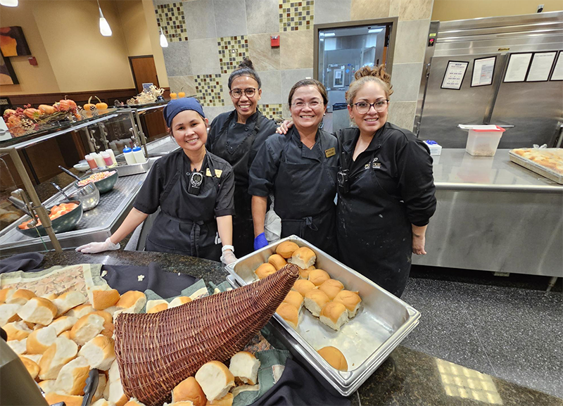 Dining staff set out dinner rolls for Thanksgiving meal.